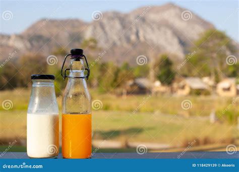 Fresh Milk And Orange Juice In Bottles Put Together With Mountain View
