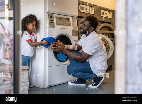 Man and his daughter putting laundry into a washer Stock Photo - Alamy