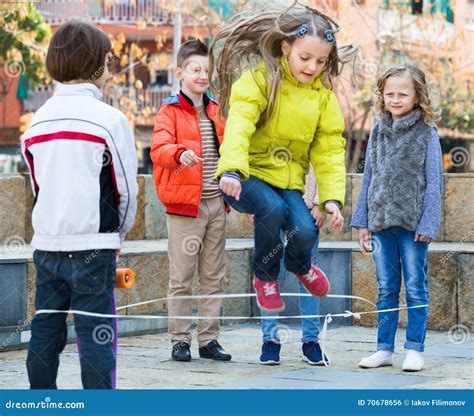 Girl Jumping While Jump Rope Game With Friends Stock Photo Image Of Portrait Friendship