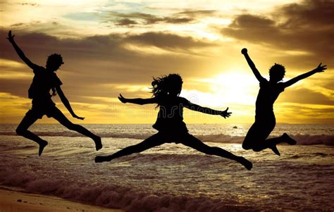 Happy Girls Jumping On The Beach At The Sunset Time Stock Photo