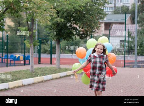 Charmante Teenager Mädchen in karierten braunen Kleid mit Haufen von bunten Luftballons
