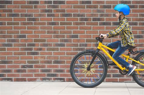 Profile View Of Boy In Helmet Riding Bike On Sidewalk Against