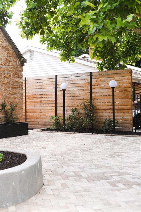 A Wooden Privacy Fence With Tall Outdoor Lights In Front Of It In 2021