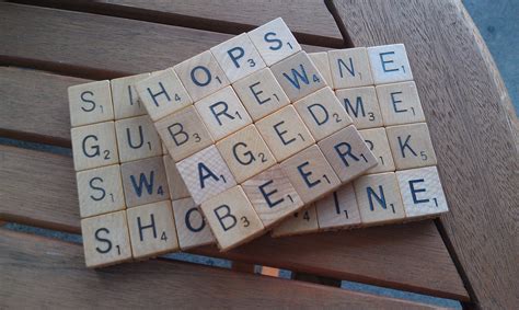 Several Scrabble Tiles Sitting On Top Of A Wooden Bench With Words