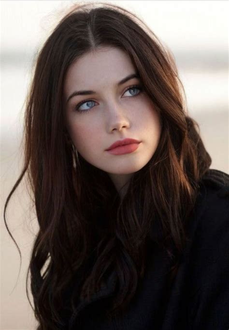 A Woman With Long Brown Hair And Blue Eyes Is Posing For A Photo On The