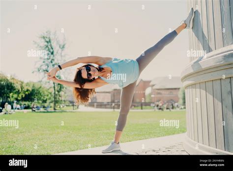 Full Length Shot Of Active Woman Stretches Legs And Arms Stays Always