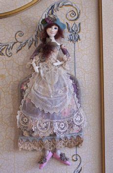 A Doll Is Hanging On The Wall Next To A Frame With An Ornate Border Around It