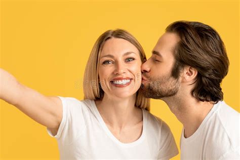 Happy Millennial Caucasian Husband Kissing Wife On Cheek In White T