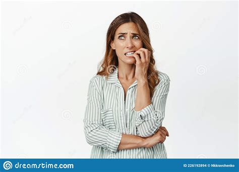 Portrait Of Nervous Brunette Woman Biting Fingers And Looking Aside