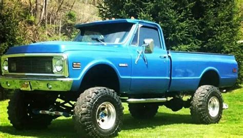 A Blue Truck Parked On Top Of A Lush Green Field