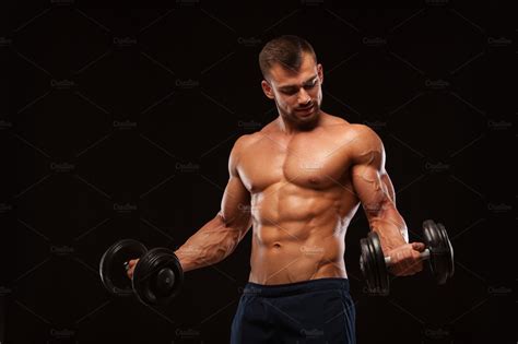 Handsome Athletic Man In Gym Is Pumping Up Muscles With Dumbbells In A Gym Fitness Muscular
