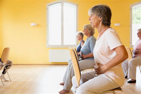 Active Senior Women Yoga Class On Chairs Doing Breathing Exercise Stock
