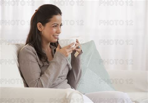 Hispanic Woman Drinking Tea On Sofa Photo12 Tetra Images Jgi Tom Grill
