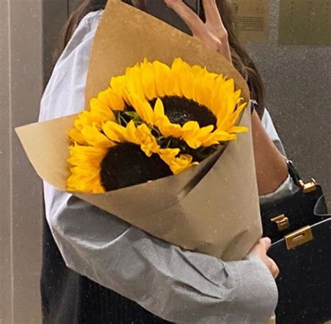 A Woman Holding A Bouquet Of Sunflowers In Front Of Her Face While
