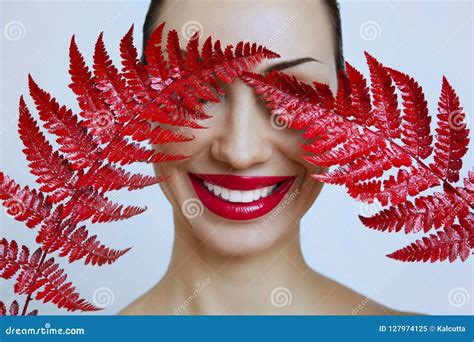 een vrouw met sensuele rode lippen en een varenblad stock afbeelding image of rood gezicht