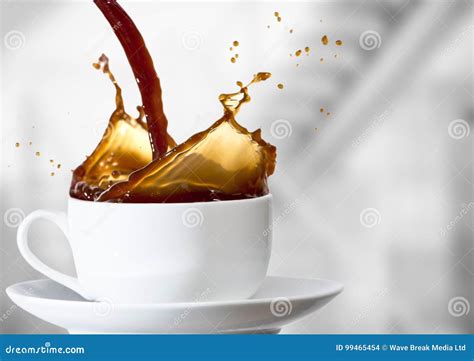 Coffee Being Poured Into White Cup Against Blurry Grey Stairs Stock
