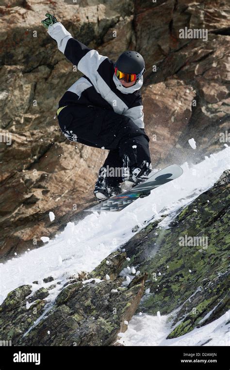 Snowboarder Jumping On Rocky Slope Stock Photo Alamy