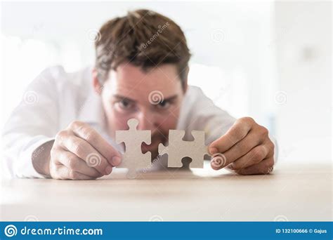 Young Businessman Joining Two Matching Puzzle Pieces Stock Photo