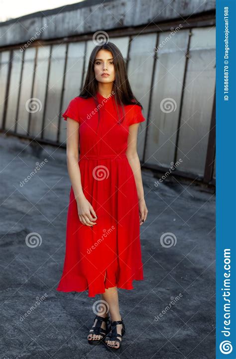 attractive beautiful shy girl in a red dress with brown straight hair looking at camera full