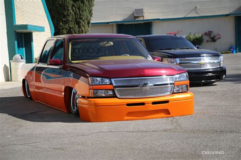 An Orange And Red Truck Parked In A Parking Lot Next To Two Other Cars