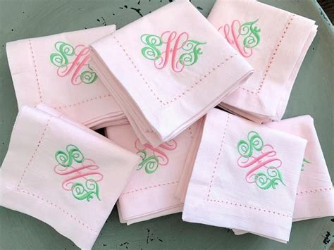 Pink And Green Embroidered Napkins With Monogrammed Letters On Them In