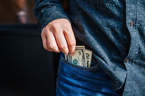 Human Hand Is Putting Money In The Pocket Stock Photo Download Image