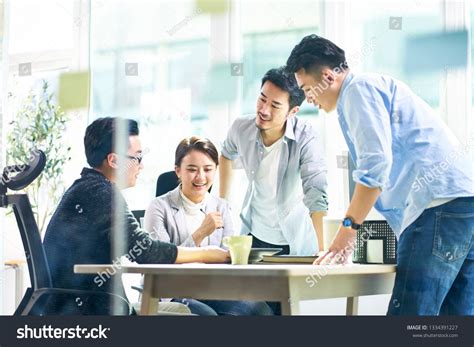 Group Of Four Happy Young Asian Corporate Executives Working Together