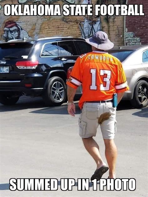 A Man In An Orange Jersey Is Skateboarding Down The Street With Cars
