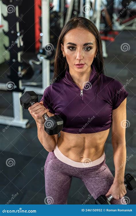 Young Woman Trainer With Beautiful Press On Her Stomach And Strong Hands Trains In The Gym