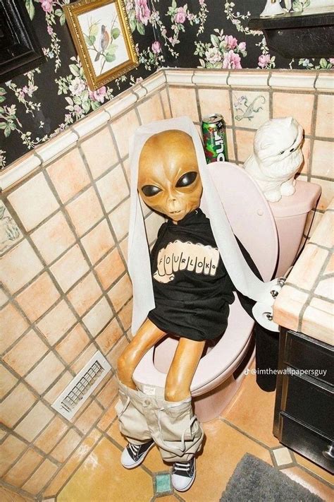 An Alien Doll Sitting On Top Of A Toilet In A Bathroom