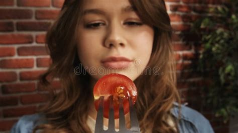 Close Up Of A Girl Looking At A Fork With Half Of A Ripe Red Cherry