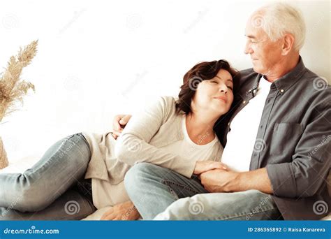 Mature 60 Year Old Couple Hugging While Sitting On The Bed In The