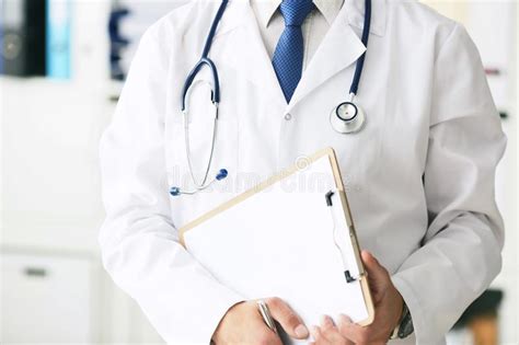 Close Up Of Clipboard With Blank Paper In Medical Doctor Hand Male