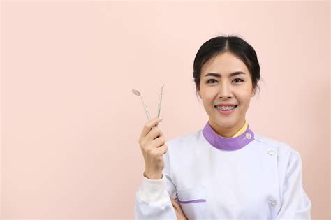 Premium Photo Asian Woman Dentist Standing With Dental Orthodontic Tool In Hand With Pink Wall