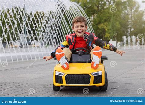 Cute Little Boy Driving Children S Car Near Fountain On City Street