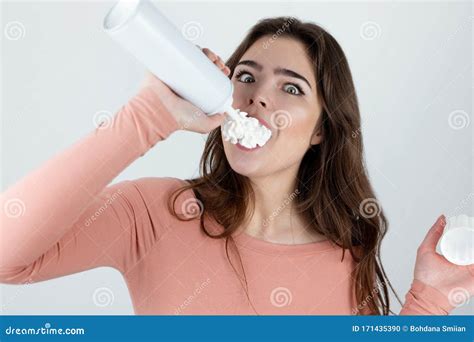 Young Beautiful Woman Putting Whipped Cream Directly To Her Mouth Looking Amazed Standing On