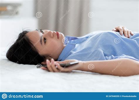 Depressed Woman Laying On Bed With Smartphone In Her Hand Stock Image