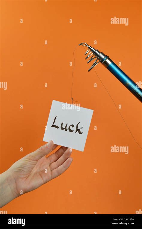 A Hand Grabbing For A Piece Of Paper With The Word LUCK On It Hanging From A Fishing Line Stock