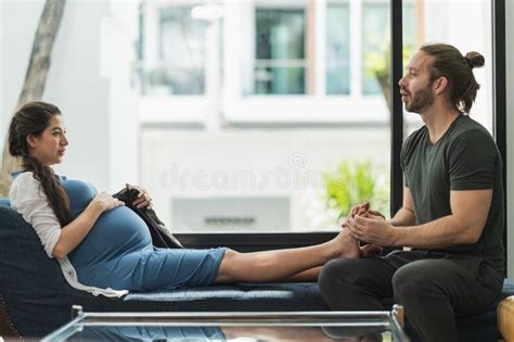 Beard Man Doing Foot Massage His Pregnant Wife While Sitting On Sofa In They Home Stock Image