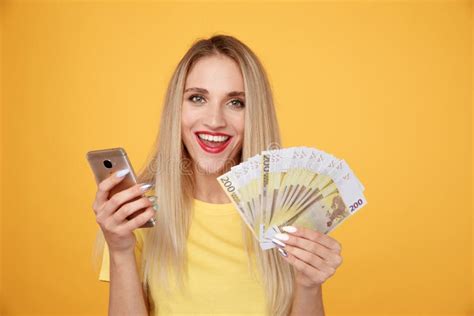 Happy Girl With Mobile And Cash Isolated On The Yellow Background