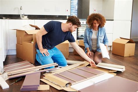 Couple Putting Together Self Assembly Furniture In New Home Stock Image