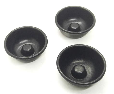 Three Black Bowls Sitting On Top Of A White Table