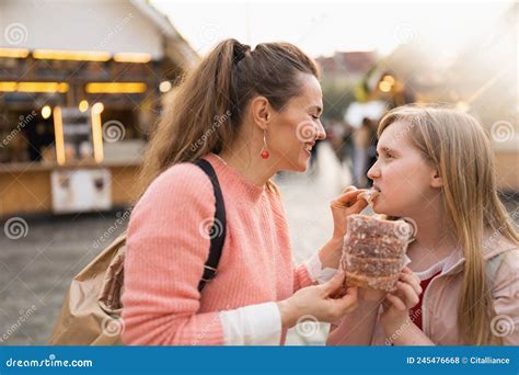 Happy Mother And Daughter At Fair In City Eating Trdelnik Stock Photo