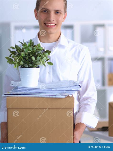 Young Man Holding A Stack Of Cardboard Boxes Standing In Office Stock