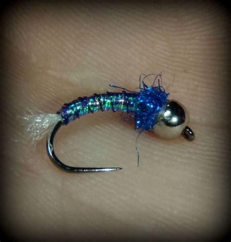 A Close Up Of A Fishing Lure On A Persons Hand With Blue And Green Beads