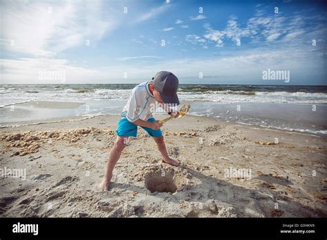 Boy On Beach Digging Hole In Sand Stock Photo Alamy
