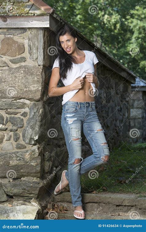 piękna brunetki kobiety pozycja w białej koszulce cajgach i ogród zdjęcie stock obraz