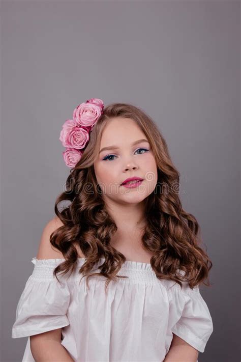 Brunette Teenage Girl With Pink Roses In Her Hair On Gray Background