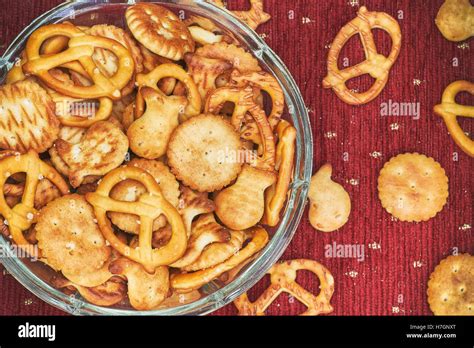 Mix Of Salty Snacks Crackers And Pretzels In Glass Bowl On Red