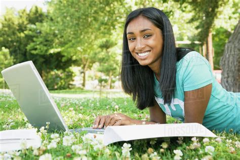 Indian Female College Student Working On Laptop In Grass Stock Photo